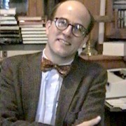Balding man in his mid-40s wearing a tweed blazer and a bow tie